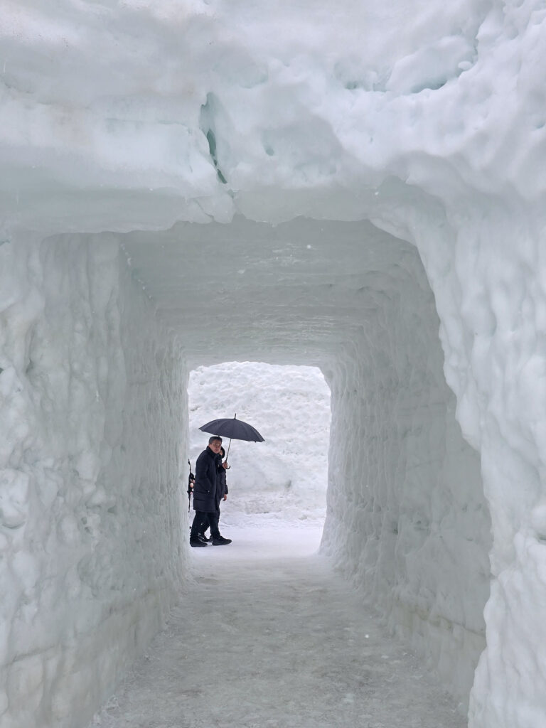 Un tunnel de neige ou une homme passe avec un parapluie
