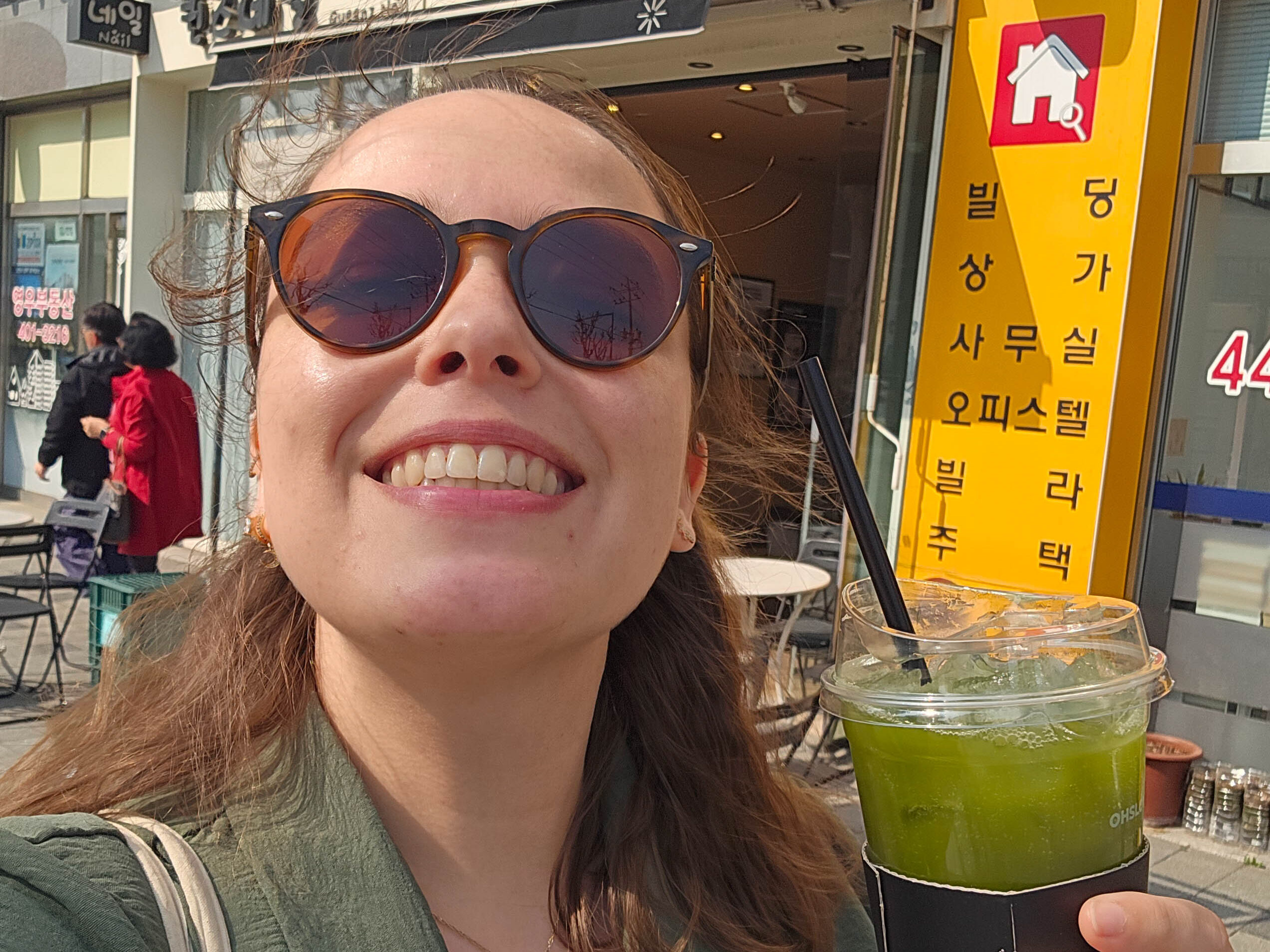 Jeune femme buvant un thé froid matcha dans une rue de Seoul.